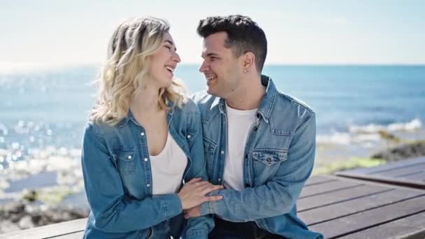 Mies ja nainen pari halaavat toisiaan istuen penkillä meren rannalla - Materiaali, video