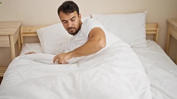 Fiatal spanyol férfi felébred az ágyon ülve a hálószobában. - Felvétel, videó