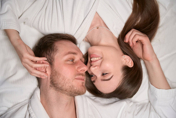 Vista superior de romántico joven mujer y hombre acostado en la cama y mirándose el uno al otro - Foto, Imagen
