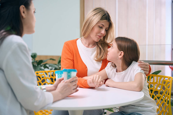 Caring mother calming down little daughter talking to pediatrician about health problems and proper treatment, timely diagnosis - 写真・画像
