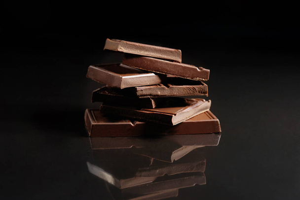 Milk chocolate with reflection on a black background. - Фото, изображение