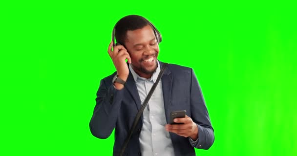 Biznesmen, słuchawki i telefon na zielonym ekranie z uśmiechem, muzyką i torbą na podróż. czarny mężczyzna przedsiębiorca w studio tło z smartfon dla streaming, taniec i szczęśliwy. - Materiał filmowy, wideo