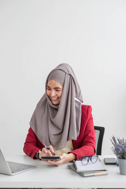 muslim businesswoman using calculator and laptop for do math finance on wooden desk in office and business working background, tax, accounting, statistics and analytic research concept - Photo, Image