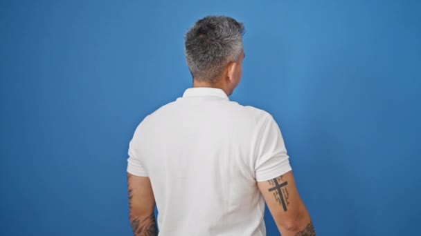Молодий іспаномовний чоловік посміхається впевнено стоїть над ізольованим синім тлом
 - Кадри, відео