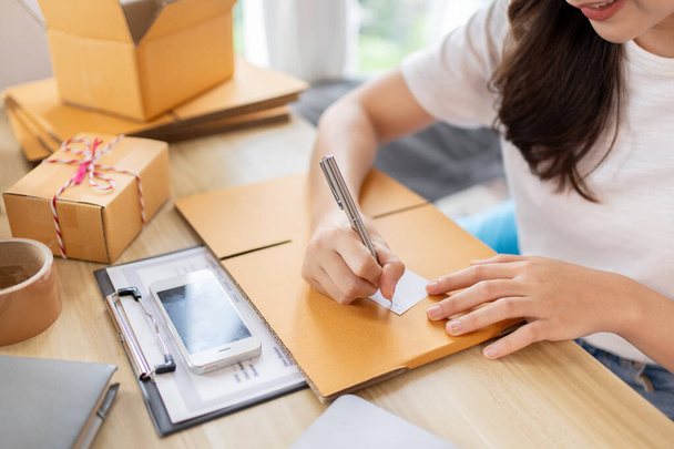 Woman Writing Customer Details for Shipping in Home Office, Packing Box and Writing Customer Information for Efficient Shipping, E-Commerce and Online Selling Concept. - Фото, зображення