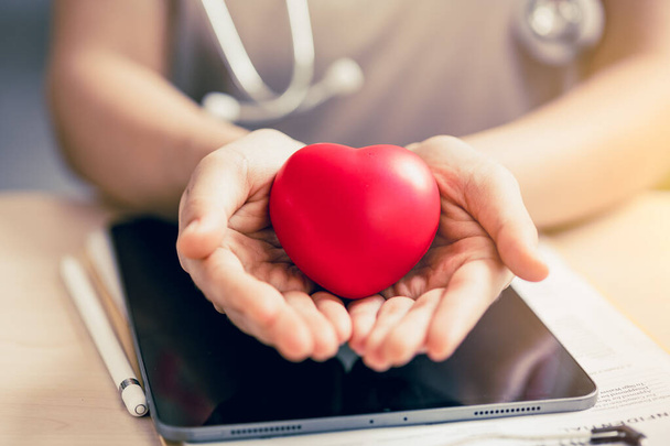 Doktor eli kırmızı kalp işareti vererek sağlıklı kalbi olan insanlara destek oluyor ve hipertansiyon kalp krizi korumasına yönelik farkındalığı artırıyor.. - Fotoğraf, Görsel