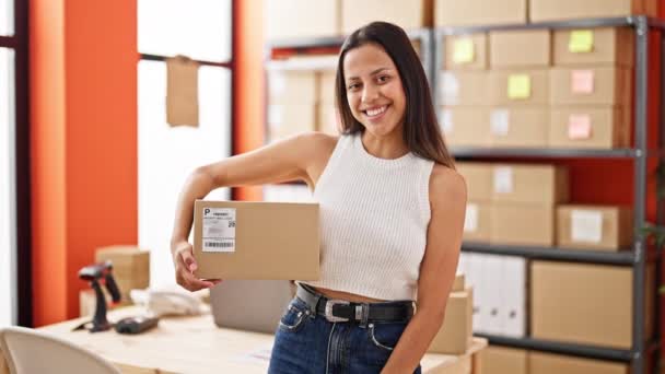 Young beautiful hispanic woman ecommerce business worker holding package at office - Séquence, vidéo