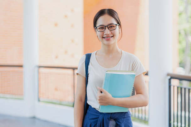 Portret azjatycki nastolatek dziewczyna szczęśliwy uśmiech w uniwersytet kampus cieszyć się nauka ludzie. - Zdjęcie, obraz
