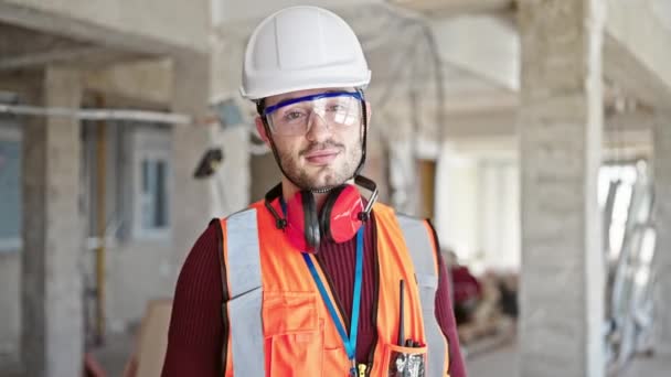 jovem hispânico homem construtor sorrindo confiante em pé no local de construção - Filmagem, Vídeo