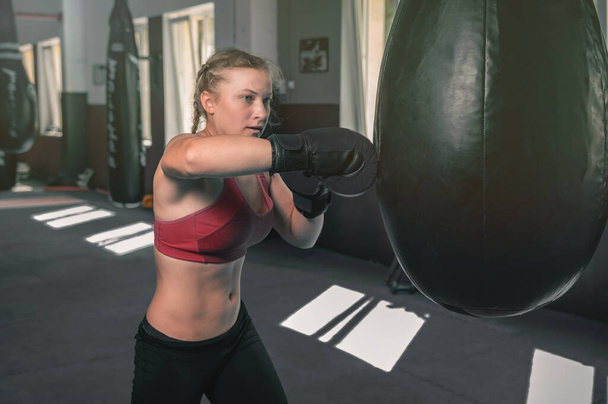 女性の自己防衛少女の力。若い女性ボクサーはジムでパンチングバッグで訓練しています。強い女戦士 - 写真・画像