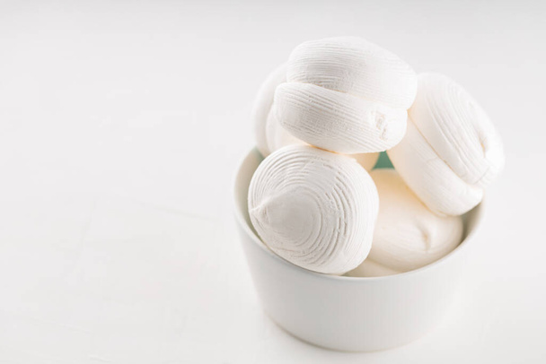 Sweet dessert white zephyr marshmallows in a bowl. Delicious zephyr marshmallows on a white background. Copy space - Foto, Imagem