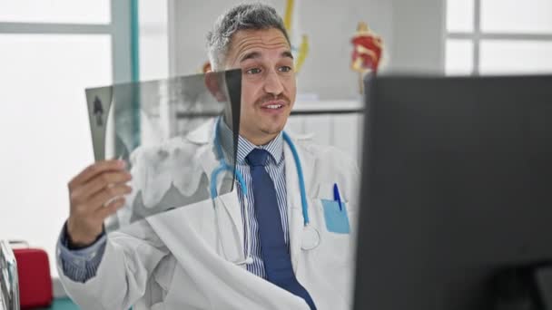 Νεαρός Ισπανός γιατρός σε ραντεβού στο διαδίκτυο που δείχνει ακτινογραφία στην κλινική - Πλάνα, βίντεο