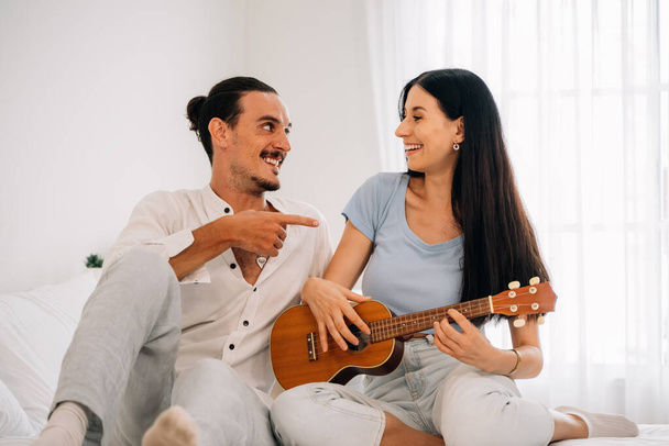 Happy man and woman enjoying with music playing on instrument, Young couple playing ukulele guitar at home, Happy young couple spend time together at home, Family and lovers lifestyle - Fotografie, Obrázek