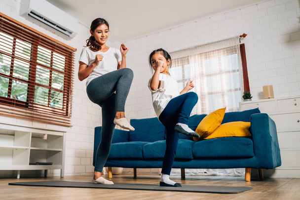 Genç anne ve kızı evde oturma odasında egzersiz yapıyor sağlıklı ve sağlıklı bir aile evde yoga egzersizi yapıyor evde birlikte oynuyorlar sağlıklı yaşam tarzına sahip bir aile. - Fotoğraf, Görsel