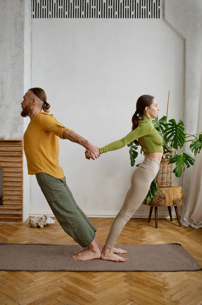 Para ćwicząca jogę w parze, robiąca razem akrobatyczne deski. Millennial mężczyzna i kobieta robi ćwiczenia równoważenia - Zdjęcie, obraz