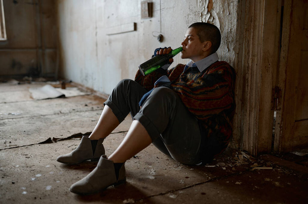 幸せな失業ホームレスの女性が最高の人生を夢見て床に座ってビールを飲む - 写真・画像