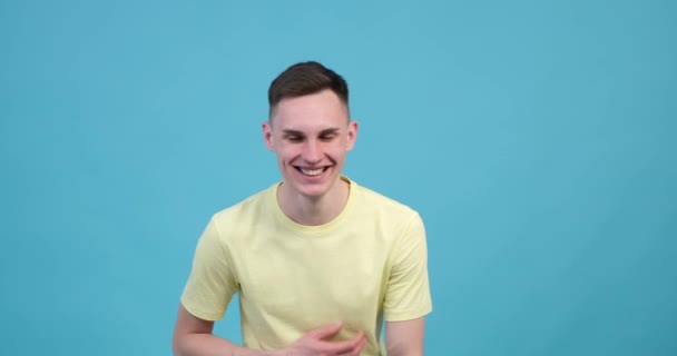A jovial Caucasian man on the blue background bursts into laughter, unable to contain his infectious sense of humor. His eyes crinkle with mirth, and his mouth forms a wide. - Footage, Video
