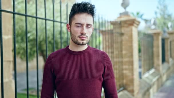 Jonge Spaanse man met serieuze uitdrukking en armen gekruist gebaar op straat - Video