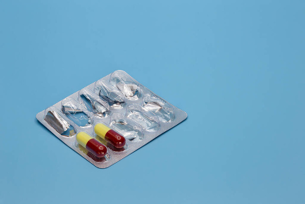 Pillole in una ciotola nera su sfondo blu. Concetto medico - Foto, immagini