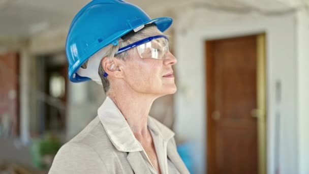 Keski-ikä blondi nainen arkkitehti seisoo rento ilme katselee ylös rakennustyömaalla - Materiaali, video