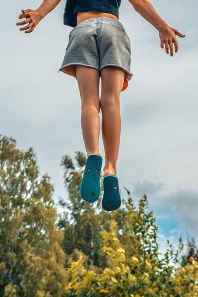 Egy gyerek ugrik a trambulinra. A lány felugrott a levegőbe. Egy pozitív érzelmű gyerek ugrik. Ugrás egy trambulinon lehet egy csodálatos és élvezetes tevékenység a gyermekek számára, elősegítve a fizikai - Fotó, kép