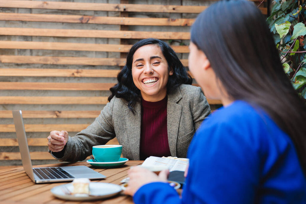 Conversação de Segurança Financeira: Jovem Mulher Latina Vendendo Seguro de Vida para Outra Mulher em um Café Aconchegante. Foto de alta qualidade - Foto, Imagem