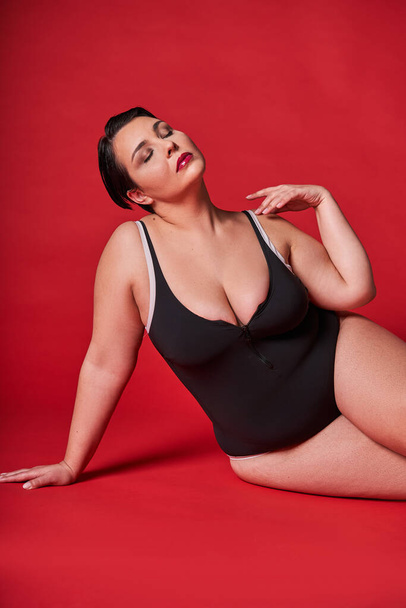Vertical view of the fat sexy woman in underwear posing on red studio background. Body positive concept. Plus size model in lingerie portrait. Girl model plus size - Φωτογραφία, εικόνα