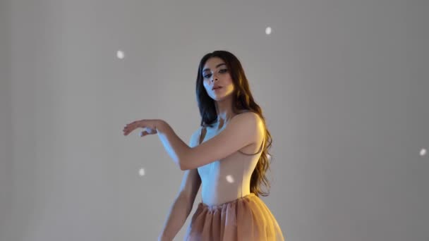 Una mujer joven, una bailarina bailando, moviendo suavemente sus brazos y dedos sobre un fondo blanco en un estudio, slow mo, medium. Señora de cabello castaño mujer con el pelo largo - Metraje, vídeo