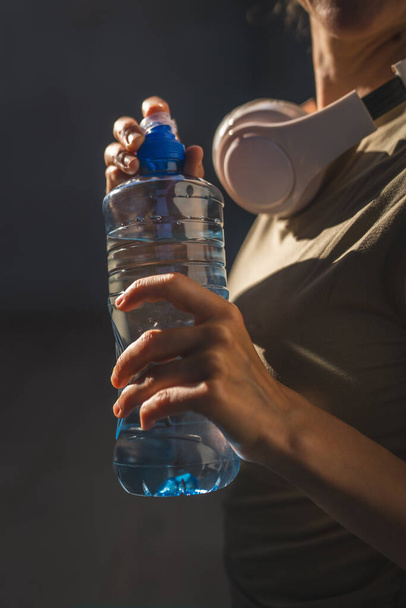close up στα χέρια στο μέσο της άγνωστης καυκάσιας γυναίκας ανοιχτό πλαστικό μπουκάλι του νερού, ενώ στέκονται υπαίθρια σε ηλιόλουστη μέρα - Φωτογραφία, εικόνα