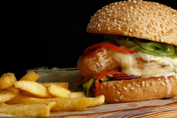Burger with French fries on a black background. Burger close-up - Φωτογραφία, εικόνα