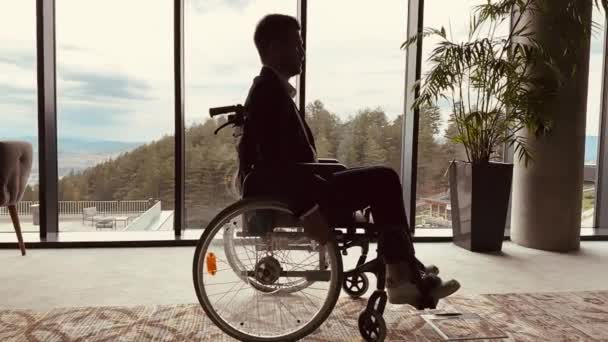 Engelli gülümseyen işadamı tekerlekli sandalyesini kullanarak modern bir ofiste eğleniyor. Özel işyeri ve verimlilik.  - Video, Çekim