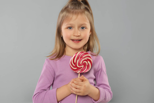 Portrait of happy girl with lollipop on light grey background - Photo, Image