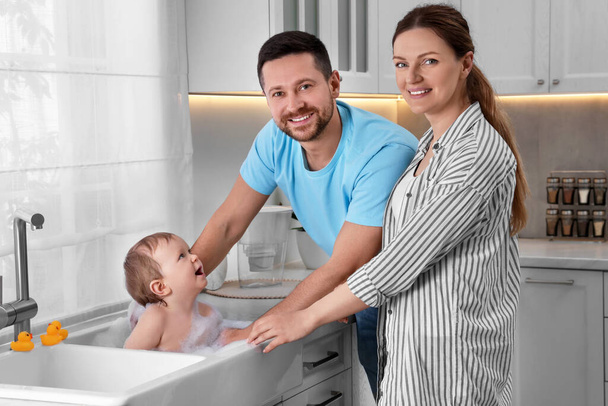 Father and mother washing their little baby in sink at home - Φωτογραφία, εικόνα