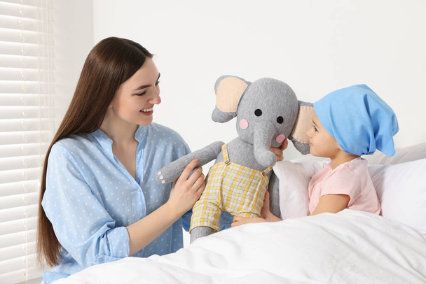 Childhood cancer. Mother and daughter with toy elephant in hospital - Foto, imagen