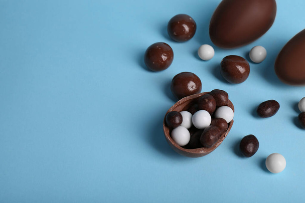 Sabrosos huevos de chocolate y diferentes dulces sobre fondo azul claro, por encima de la vista. Espacio para texto - Foto, imagen