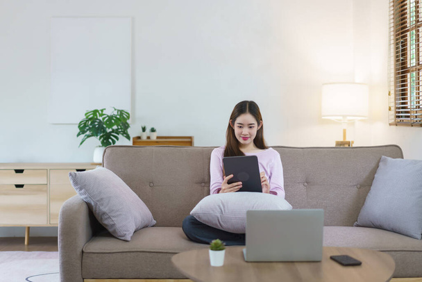 Las mujeres sentadas en el sofá grande y escribir notas en la tableta y trabajar en el ordenador portátil en el estilo de vida en casa. - Foto, Imagen