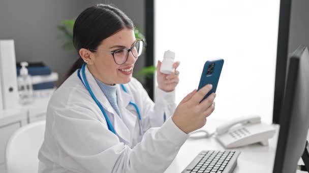 Young hispanic woman doctor using smartphone working at clinic - Footage, Video