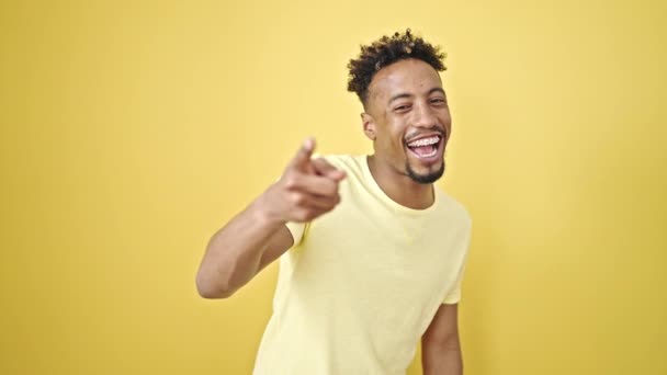 afroamericano uomo sorridente fiducioso fare gesto telefonico con mano su isolato sfondo giallo - Filmati, video