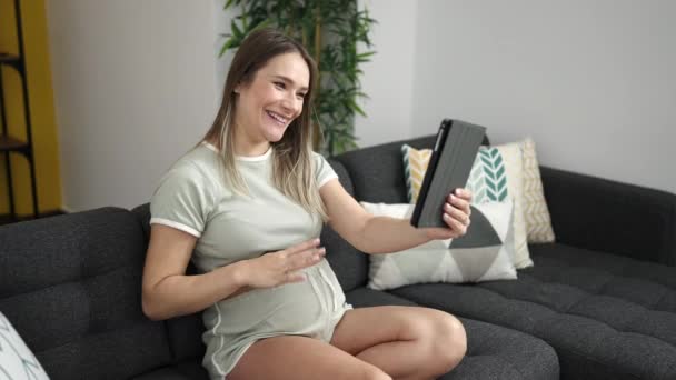 Joven embarazada teniendo videollamada tocando el vientre en casa - Imágenes, Vídeo
