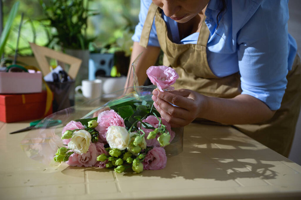 Florista de primer plano que organiza un ramo de flores de ranúnculo blanco y rosa fresco, en un estudio de diseño floral. Arreglos florales y regalos. Día de la boda. Feliz Día de las Madres y Día Internacional de la Mujer - Foto, imagen