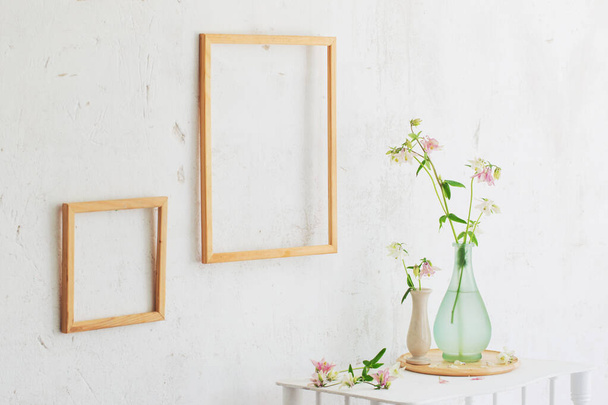 flowers in vase and wooden frames on white interior - Foto, Imagen