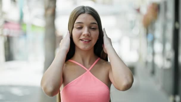 Νεαρό όμορφο κορίτσι χαμογελά αυτοπεποίθηση μιλώντας στο δρόμο - Πλάνα, βίντεο