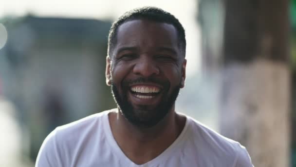 Mutlu, siyah Brezilyalı bir adam, gülerek ve gülerek şehir ortamının dışında duruyor. 30 'lu yaşlarda kendinden geçmiş Afrikalı Amerikalı neşeli erkek. - Video, Çekim