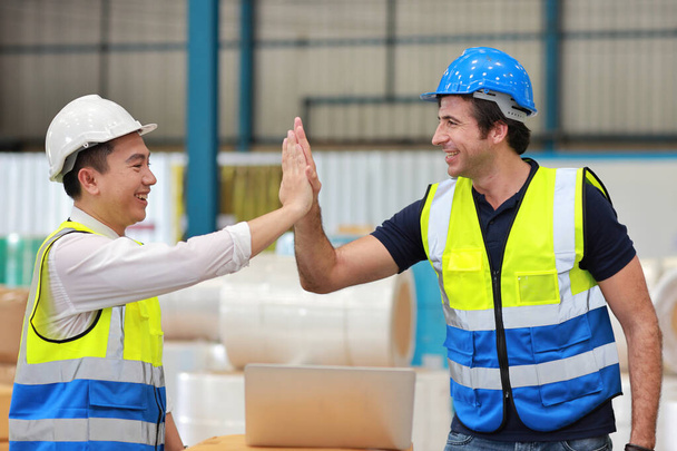 Два инженера-техник человек в защитной форме с твердой шляпой стоя и дать пять отпраздновать успех вместе или завершена сделка обязательства на промышленном складе завода - Фото, изображение