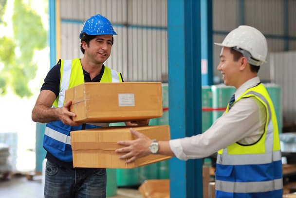 Group of warehouse worker holding boxes and taking or upload package box to shelf in large warehouse. Active caucasian business manager controlling work at warehouse industry building.  - Fotó, kép