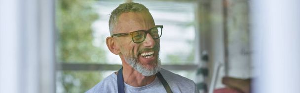 Happy middle aged caucasian man in apron aand glasses smiling looking sideways. Gardening concept. Small business - Photo, image