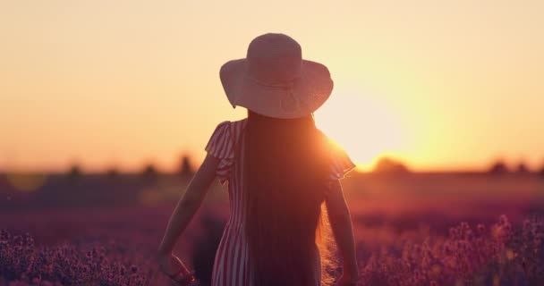 Frau, schönes Mädchen mit Kleid, Hut und Blumenstrauß genießt blühendes Lavendelfeld bei Sonnenaufgang 4K-Video - Filmmaterial, Video