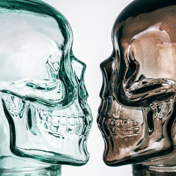 灰色の背景に2色のガラスの頭蓋骨 - 写真・画像
