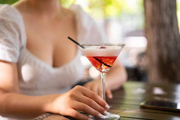 Young cute woman drinking cocktail in summer and enjoying her vacation, close-up - Foto, afbeelding