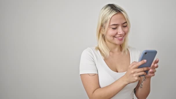 Jonge mooie Spaanse vrouw glimlachen zelfverzekerd met behulp van smartphone over geïsoleerde witte achtergrond - Video